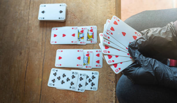 giovane donna che gioca a carte da sola a casa indossando guanti medici, solitaria (mentre era confinata a casa). - solitare foto e immagini stock