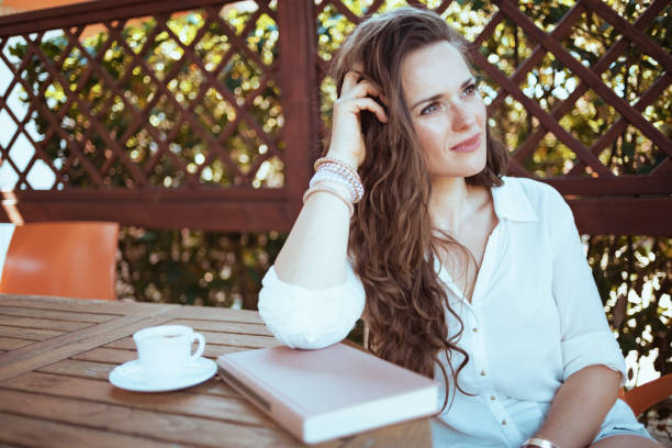 istock pensive elegant female in white shirt sitting at table 1297568111