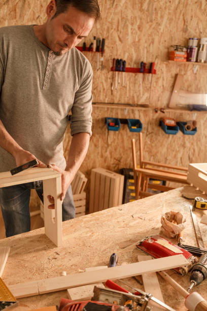 istock Diligent carpenter assembling a wooden crate with hammer and nails 1297568539