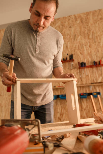 istock Diligent carpenter hammering nails in a wooden crate he is making 1297568631