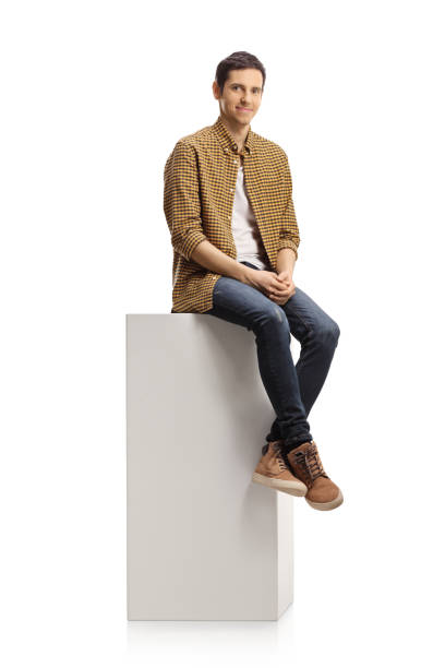 istock Casual young man sitting on a white column 1297569248