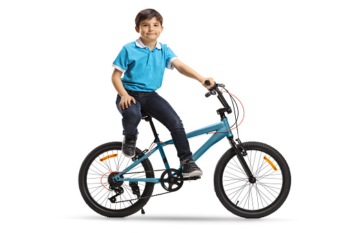 Little boy sitting on a bicycle and looking at the camera isolated on white background
