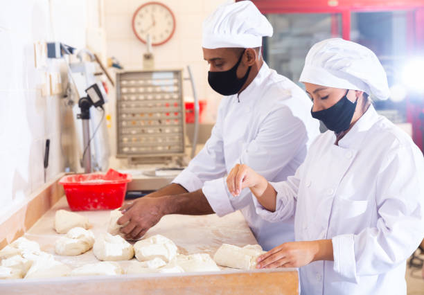 istock Skilled woman baker forming dough for baking bread 1297569741