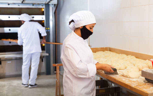 istock Woman baker preparing portioned pieces of dough for baking 1297569749