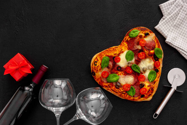 istock Valentine's day table setting. Heart pizza with wine, glasses and 1297570761