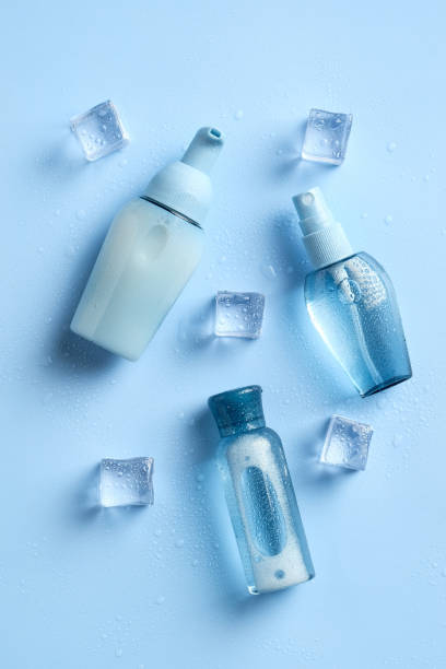 istock Hydration cosmetics collection. Transparent bottles and ice cubes on blue background. Water based cosmetics concept. 1297572360
