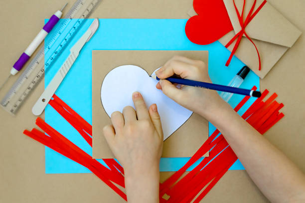 발렌타인 데이를 위한 공예품. 퀼링 방법을 사용하여 심장을 만드는 것입니다. 하트가 있는 카드를 만들기 위한 단계별 지침입니다. 3단계 - 하트 의 윤곽을 골판지 나 엽서에 복사 - pencil colors heart shape paper 뉴스 사진 이미지