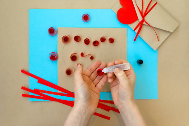 발렌타인 데이를 위한 공예품. 퀼링 방법을 사용하여 심장을 만드는 것입니다. 하트가 있는 카드를 만들기 위한 단계별 지침입니다. 7 단계 - 카드에 나선형과 접착제에 접착제를 적용합니다. - pencil colors heart shape paper 뉴스 사진 이미지
