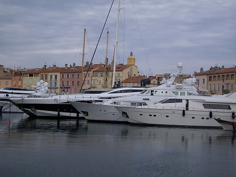 Saint Tropez, France - Mai 06th 2018:The harbor with its expensive yachts with the center of the village and its historical buildings in the background at a cloudy day in spring.