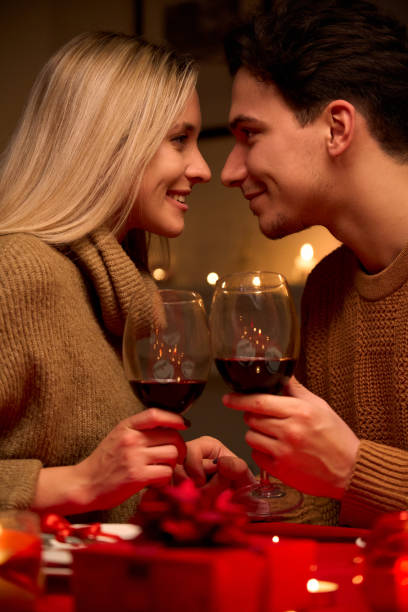 사랑의 본딩, 안경 들고, 와인을 마시는 행복한 젊은 부부는 집 테이블이나 레스토랑에 촛불과 낭만적 인 저녁 식사 데이트를하는 발렌타인 데이를 축하하는 부드러운 순간을 함께 즐길 수 있습 - valentines day romance boyfriend vertical 뉴스 사진 이미지