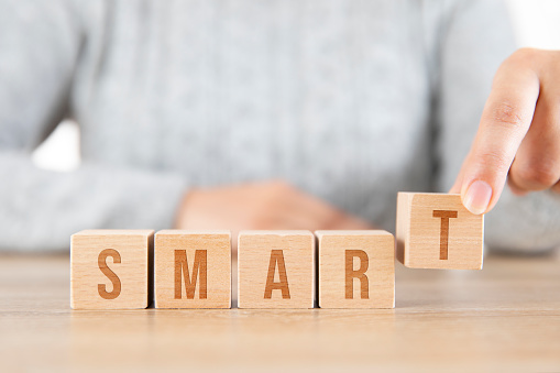 Woman is writing smart word written on wooden blocks