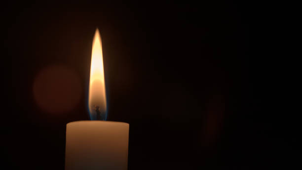 Candle flame isolated on black background in dark room close view.