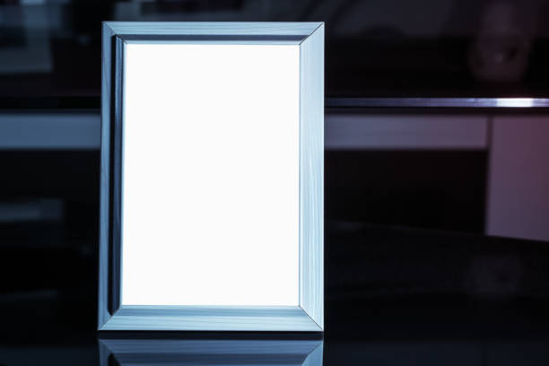 istock Empty wooden photo frame stands on table in dark room 1297585046
