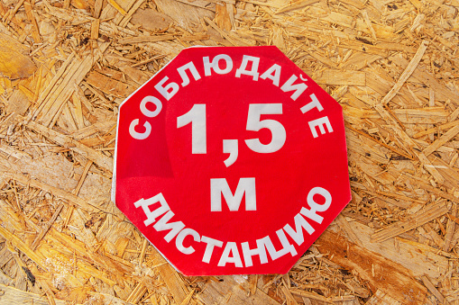 Social distancing sign on wooden background. Inscription in Russian - keep a distance of 1.5 meters.