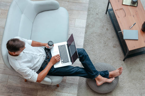 istock man with a Cup of coffee using a laptop while sitting on the sofa 1297586746