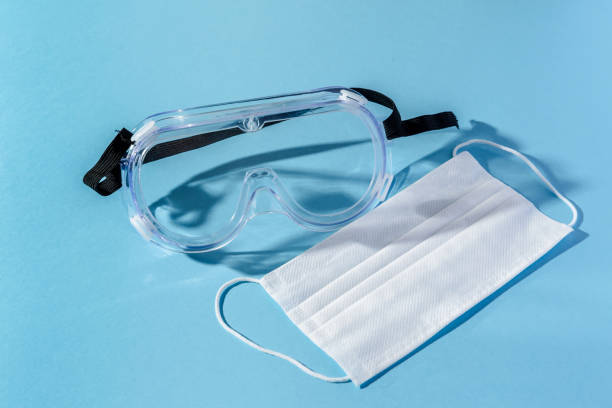 istock Surgical mask and goggles for coronavirus protection on a blue background 1297586829
