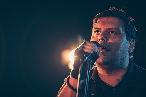 Male singer with microphone performing hard rock music on stage