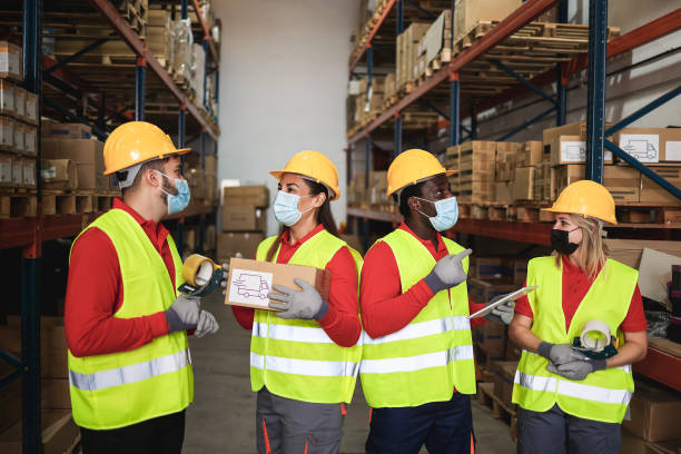 istock Happy workers talking inside warehouse while wearing safety masks during coronavirus outbreak - Focus center faces 1297589176