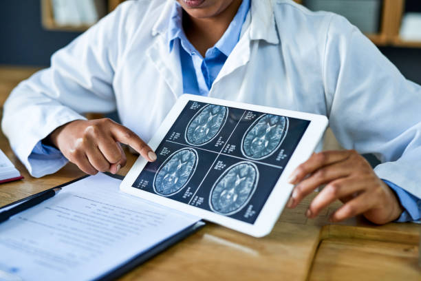 This is where the neurosurgeon takes over Shot of a doctor using a digital tablet to discuss a brain scan during a consultation in her office scientific imaging technique stock pictures, royalty-free photos & images