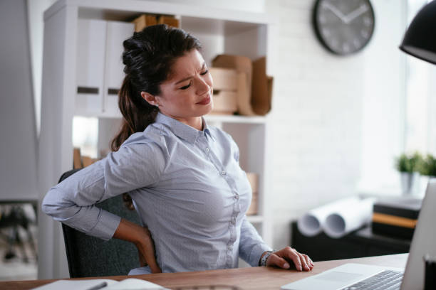 Pretty businesswoman having back pain at her workplace. Young businesswoman in the office. Pretty woman having back pain at her workplace. office back pain stock pictures, royalty-free photos & images