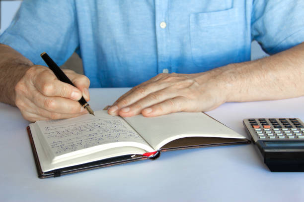 istock Hand with pen and notepad written next to a calculator. 1297590810