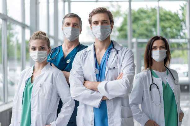 istock Group of doctors with face masks looking at camera, corona virus concept 1297593028