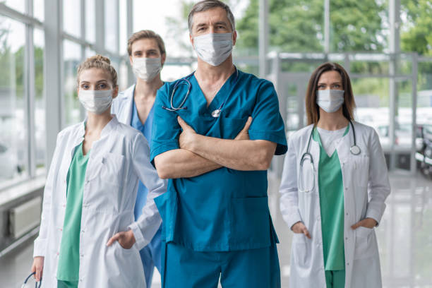 istock Group of doctors with face masks looking at camera, corona virus concept 1297593031