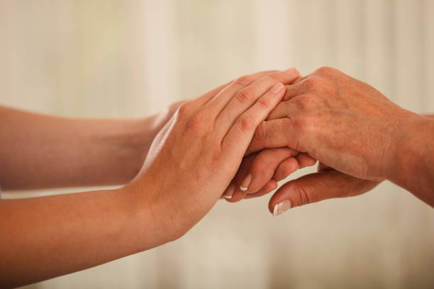 istock Young woman consoling the elderly by holding hands 1297593226