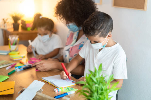 istock Children students painting draws with teacher inside preschool during coronavirus outbreak - Focus on boy face 1297594687