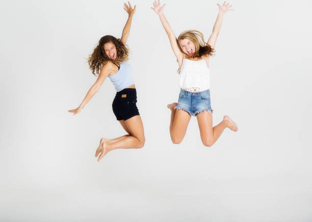 Happy young woman and her teenage friend leaping high in the air.