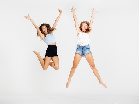 Happy young woman and her teenage friend leaping high in the air.