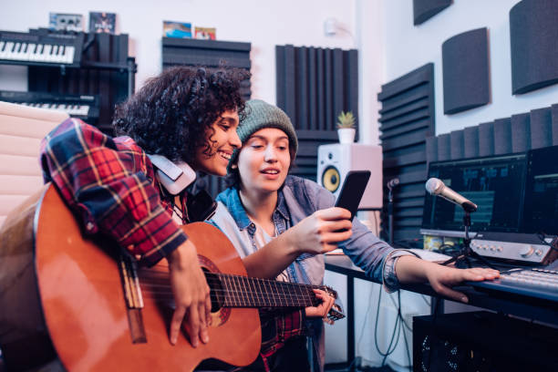 istock Two musicians recording music in the studio and using a mobile app 1297599150