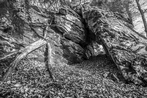 Black and White image Old weathered granite rock formation with cave and breakthrough in the forest on the Rusel and Ruselabsatz near Geisslinger Stein Koenigstein and Hausstein in the Bavarian Forest near Deggendorf and Regen, Germany