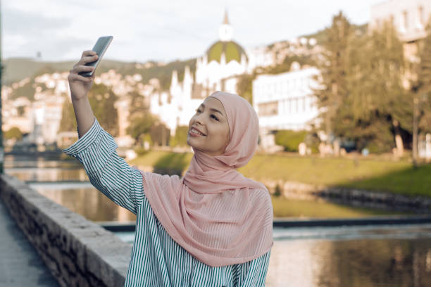 istock Beautiful woman with hijab taking a selfie by the river 1297601046