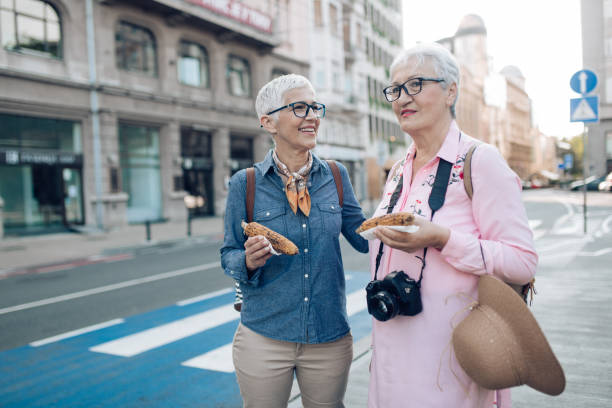 istock Two senior friends walking and snacking corn during their vacation 1297601109