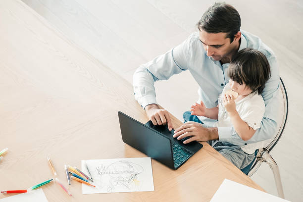 istock Focused dad using laptop and holding little son on knees 1297602583