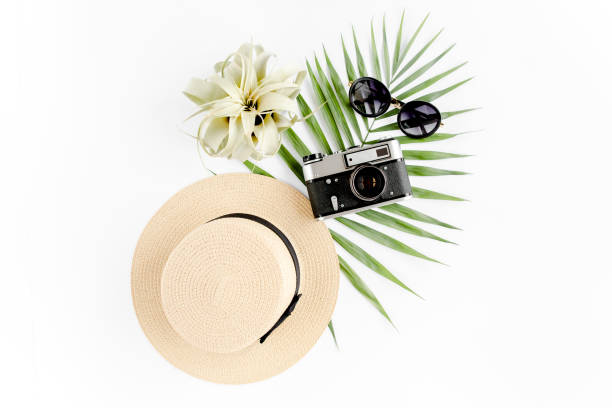 istock Flat lay traveler accessories on white background with retro camera, straw hat, sunglasses, and tropical palm leaf. Travel concept background 1297602682