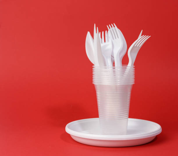istock disposable white plastic tableware plates, cups, forks and knives on a red background 1297604650