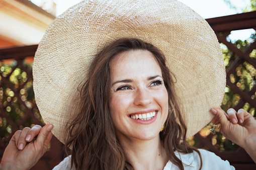 happy trendy female in white shirt with hat in the patio of guest house hotel.