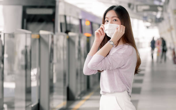 istock Woman wearing face mask and waiting for a train while standing on railway station 1297606464