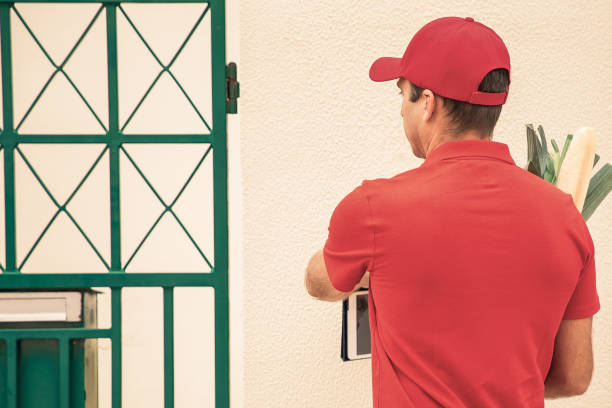 istock Back view of deliveryman ringing doorbell and holding tablet 1297607720