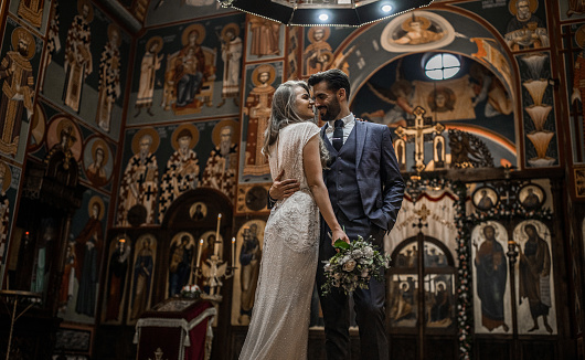Beautiful smiling young couple standing in church face to face while embracing each other