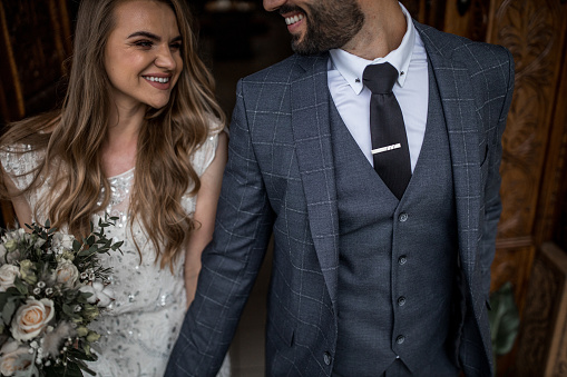 Close up of smiling young couple leaving church together while holding hands