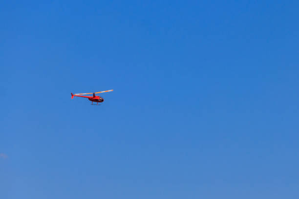 istock Flying orange helicopter in blue sky 1297610981