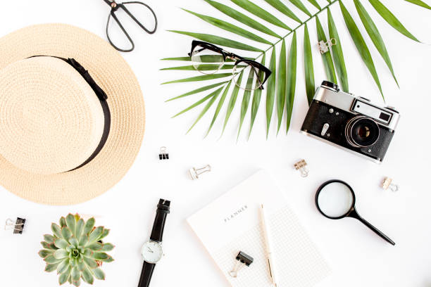 istock Top view home office desk. Workspace with straw hat, glasses, retro camera, notepad and tropical palm leaf on white background. Flat lay, top view 1297611026