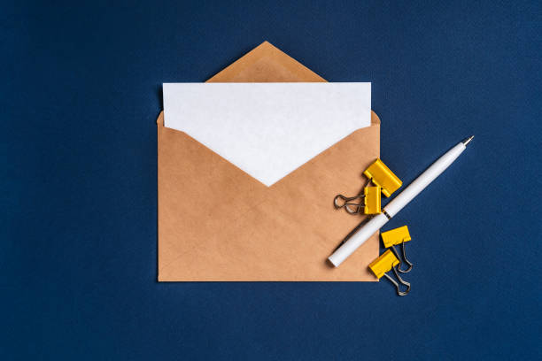 istock An envelope with a white sheet of paper on a dark blue background and a white pen. Concise, minimalist background 1297611755