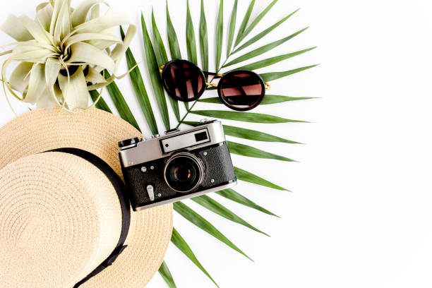 istock Flat lay traveler accessories on white background with retro camera, straw hat, sunglasses, and tropical palm leaf. Travel concept background 1297612902