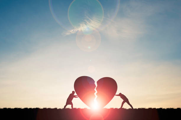istock Two silhouette men pushing broken heart with sunlight and blue sky , Valentine 's day concept. 1297613116