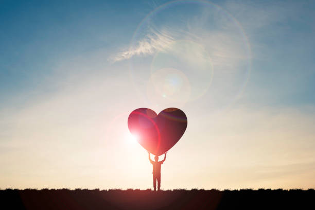 silhouette mann zeigen zwei hand aufsteigen und tragen herz mit sonnenlicht und blauen himmel, valentinstag konzept. - wohltätigkeit stock-fotos und bilder