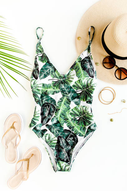 istock Woman's beach accessories: swimsuit with tropical print, straw hat on white background. Summer background 1297614691